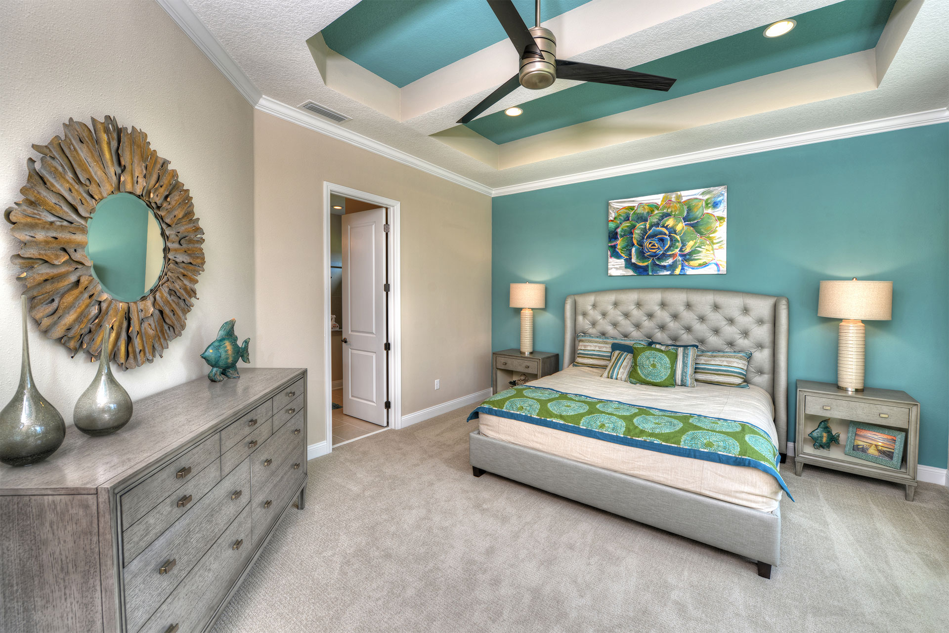 A large bedroom with a bed and dresser surrounded by two lamps.