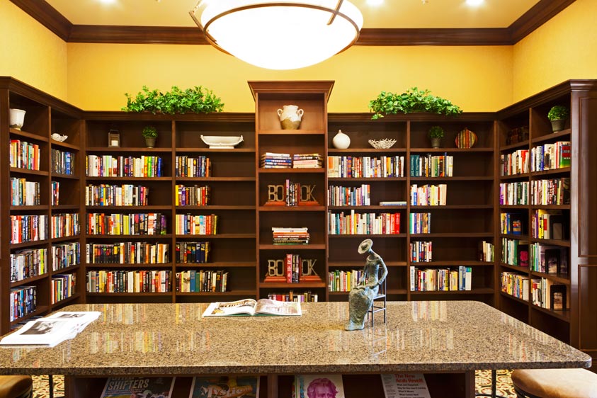 interior of a library with book shelves lining the wall and a marble tab in the middle