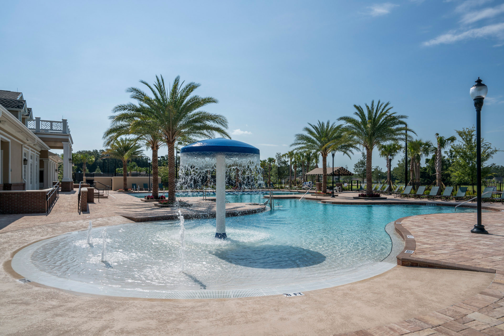 A pool with a fountain overlooking palm trees